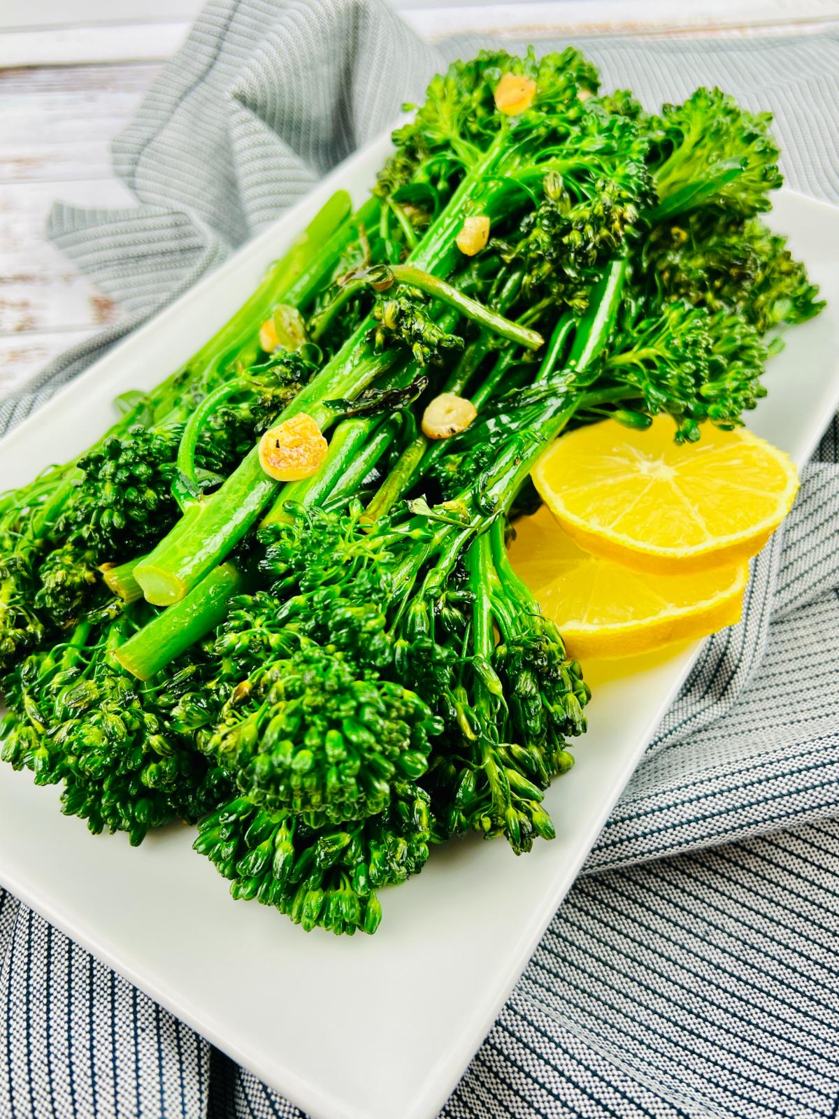 A plate of cooked Tenderstem broccoli garnished with lemon slices.