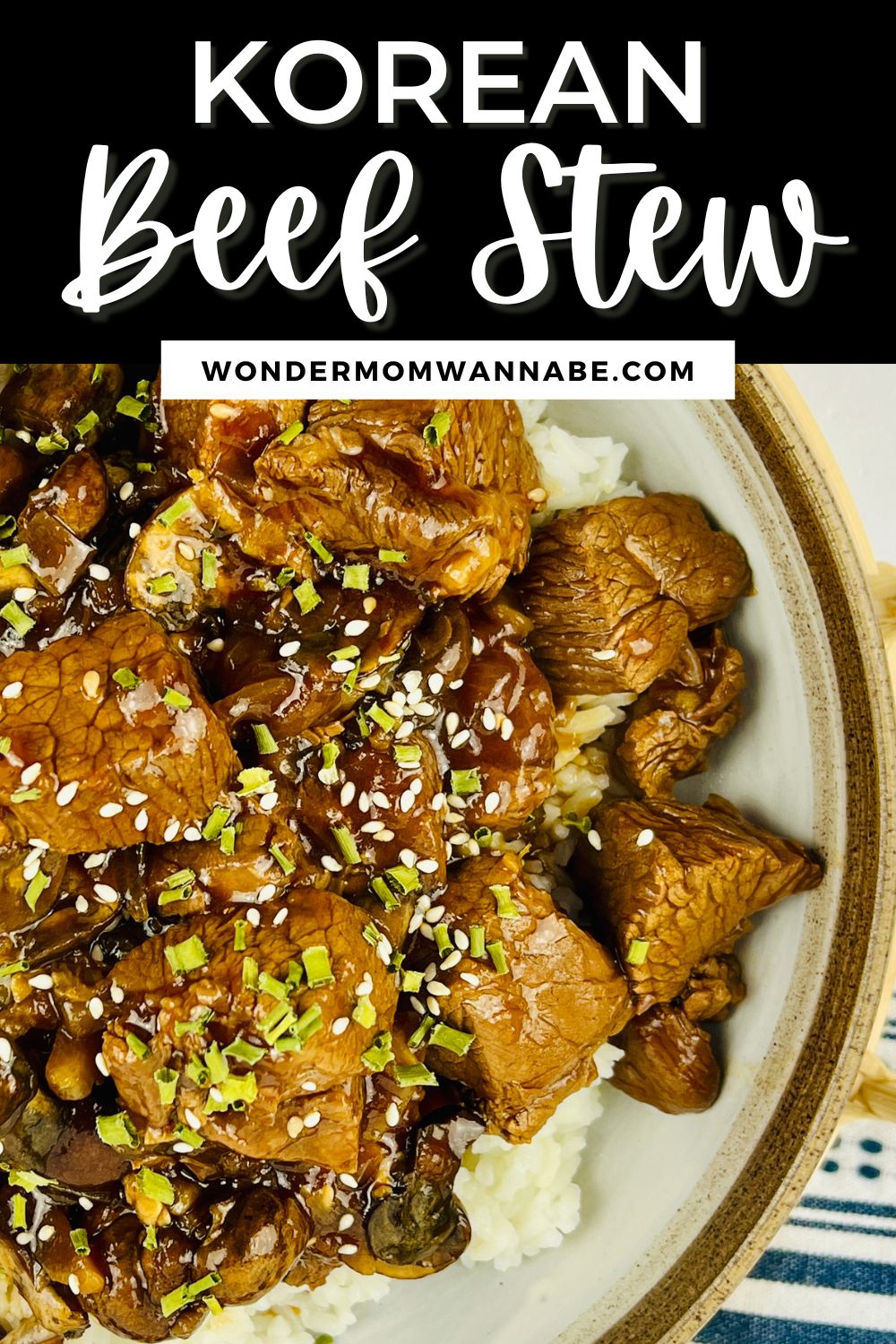 A bowl of Korean beef stew served over rice, topped with sesame seeds and garnished with green herbs, from wondermomwannabe.com.