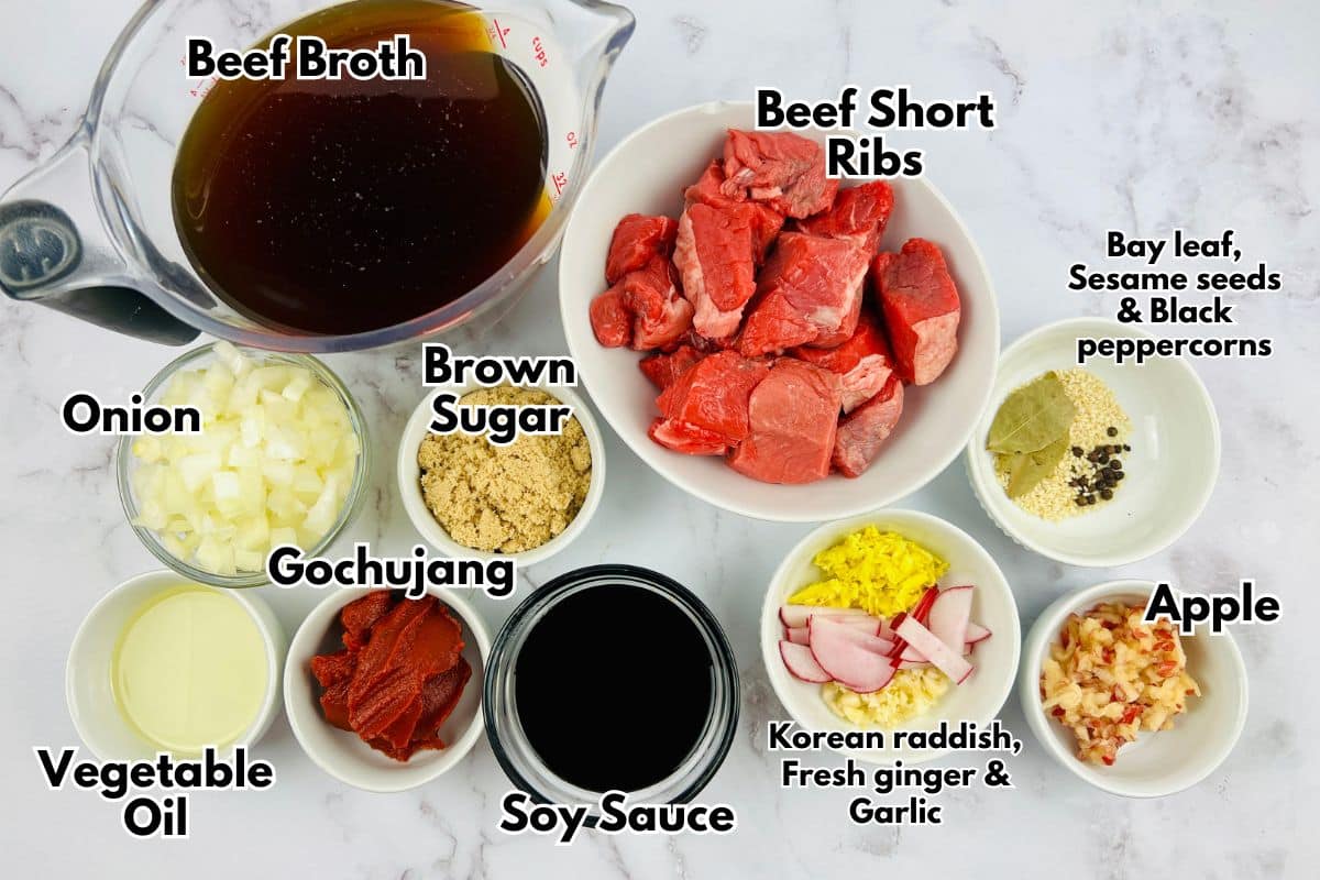 Ingredients for a Korean beef stew dish laid out in bowls on a marble surface.