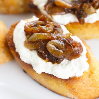 A toasted bread slice topped with creamy ricotta cheese and sweet caramelized onions, inspired by delicious caramelized onion and goat cheese bites.